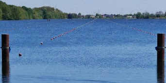 Blick entlang eines Flusses mit Bahnabsperrungen für Bootsregatta