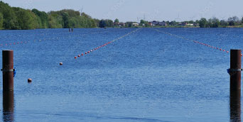 Blick entlang eines Flusses mit Bahnabsperrungen für Bootsregatta