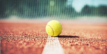 Detailansicht einer Linie auf dem Tennisplatz, mit Tennisball im Fokus, der auf der Linie liegt